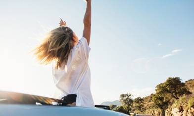 lady waving her arms in an open top car