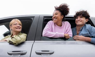 a driver and two passengers all leaning out of windows and smiling