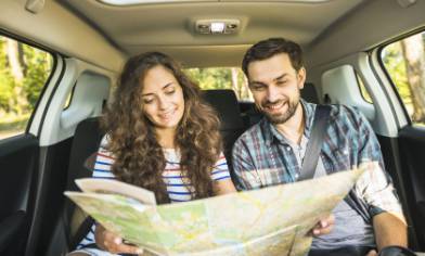Two people sitting in the back of a parked car looking at a map
