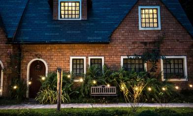 two storey pitched roof house at night with light in the upper windows and in the garden