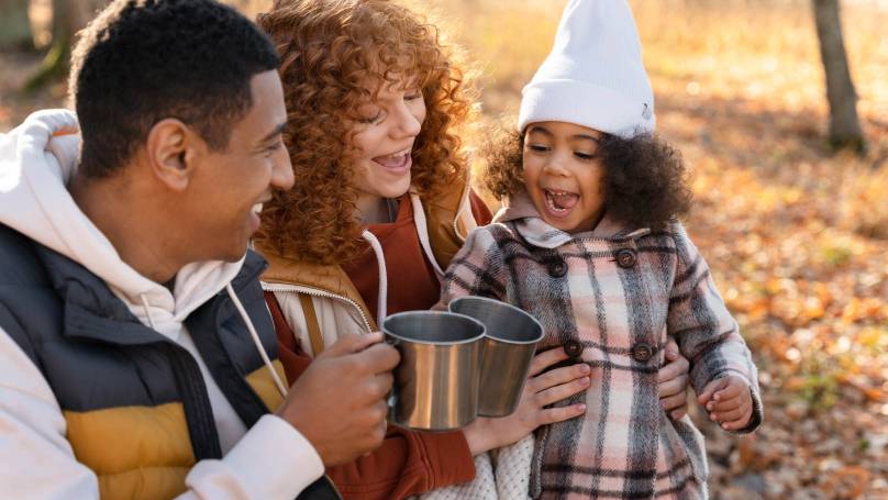 a happy family drinking tea whilst camping
