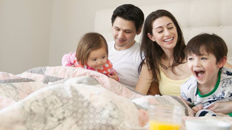 Young family laughing in bed together