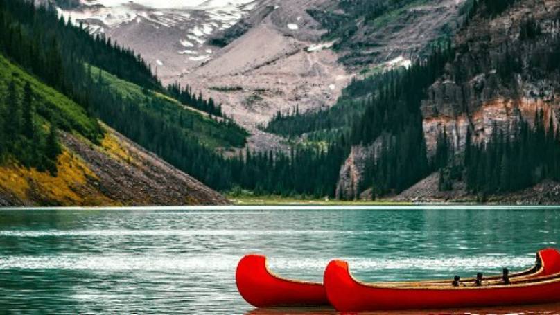 Canadian kayaks in water surrounded by Canadian mountains and trees