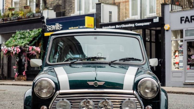 Vintage green mini car in front of High street shops