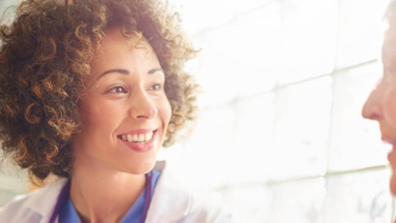 Female doctor smiling and talking to an elderly female patient