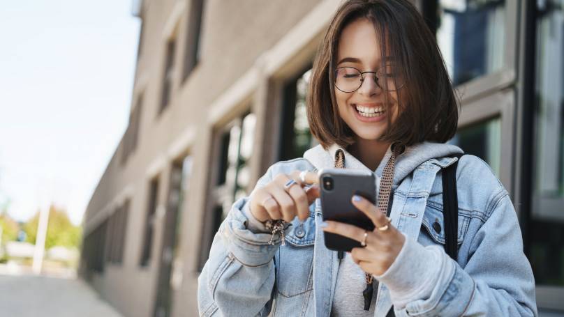 a student happily scrolling on their smartphone