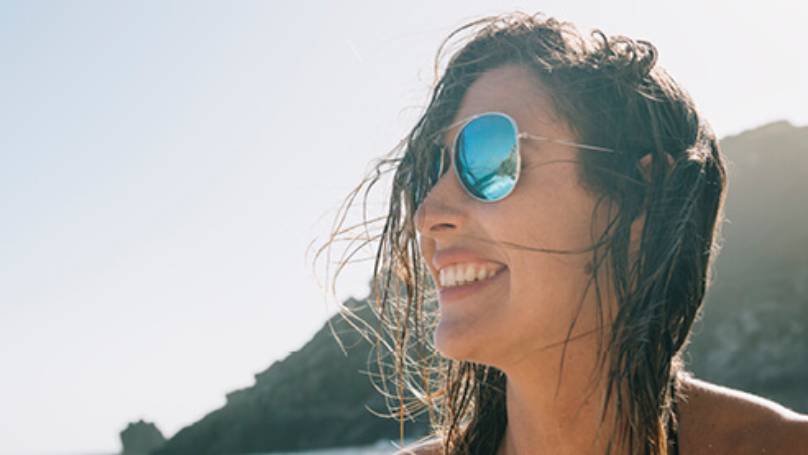 Woman wearing sunglasses and smiling with mountains in distance