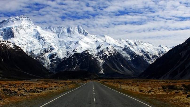 New Zealand road with snow-capped mountains either side and ahead