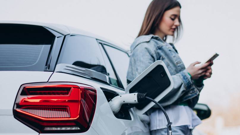 Woman charging her electric car with charging pistol