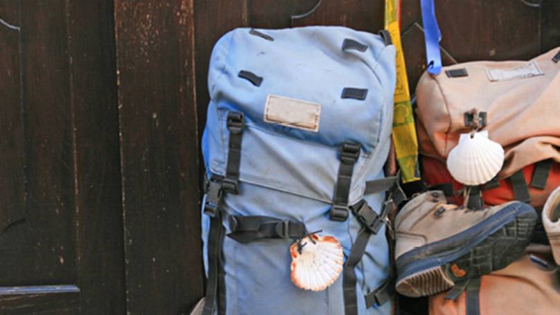 Two backpacks, one with boots attached, sat against a dark wooden door