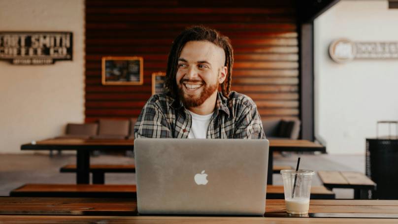 A person sitting at a table working on a laptop, in a room with modern decor.