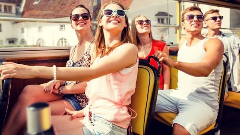 A group of friends on the top deck of a tourist bus
