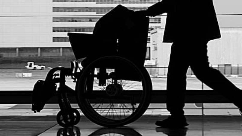 Person pushing wheelchair along passage in airport