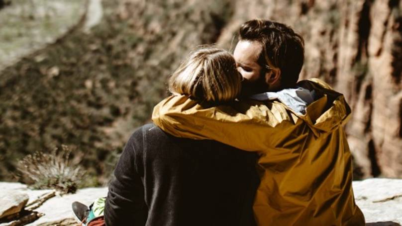 Couple sitting on rock hill, embracing