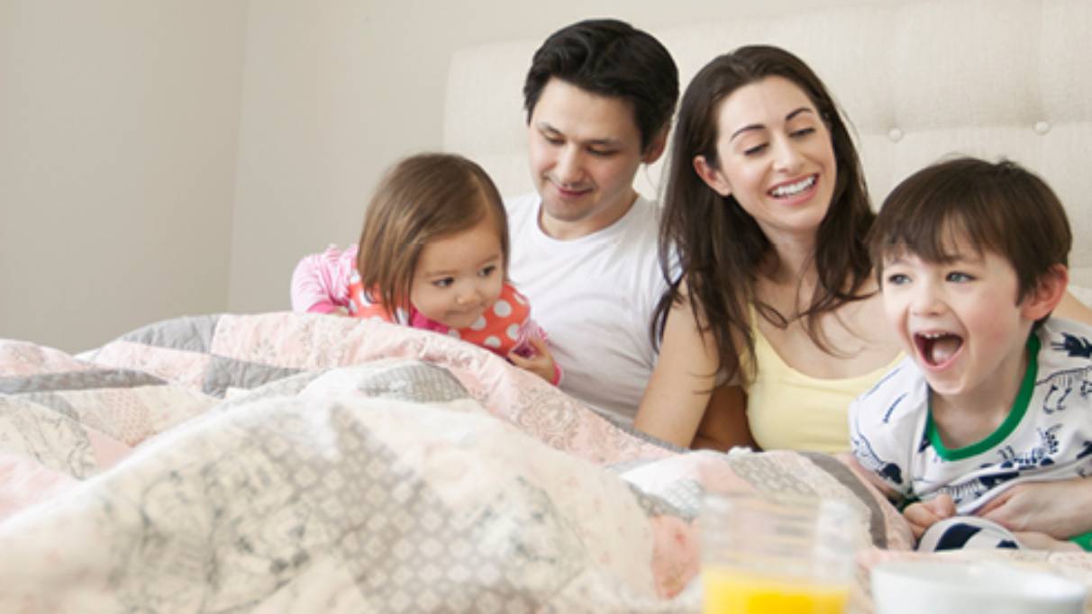 Young family laughing in bed together