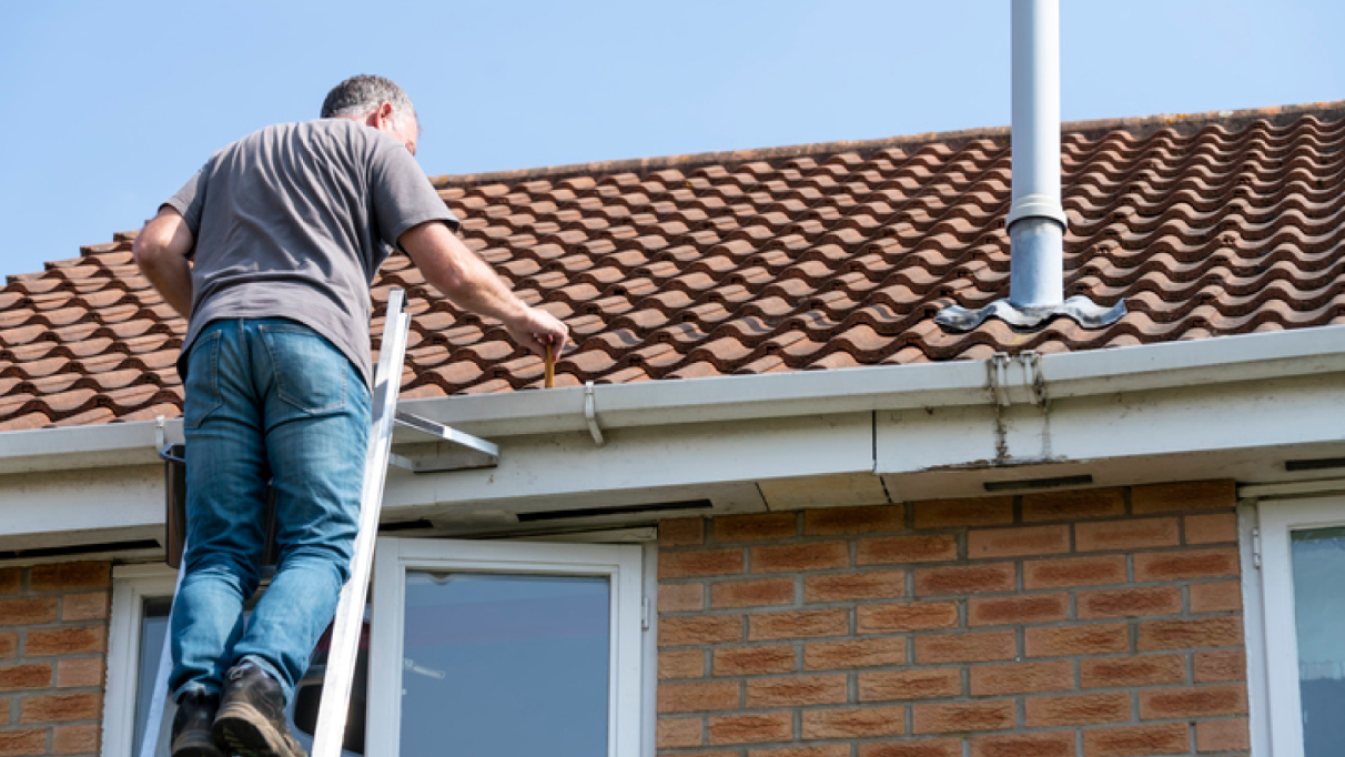 man clearing the gutter from the roof