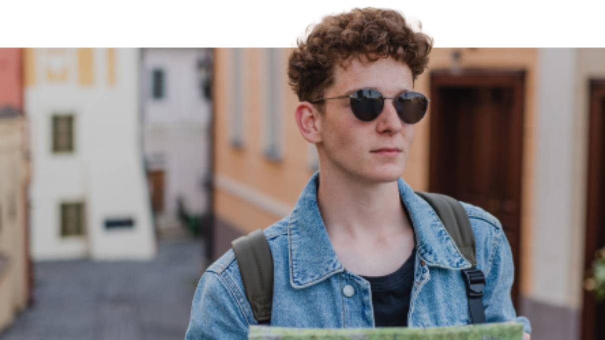 Man wearing sunglasses in a European city holding a map 