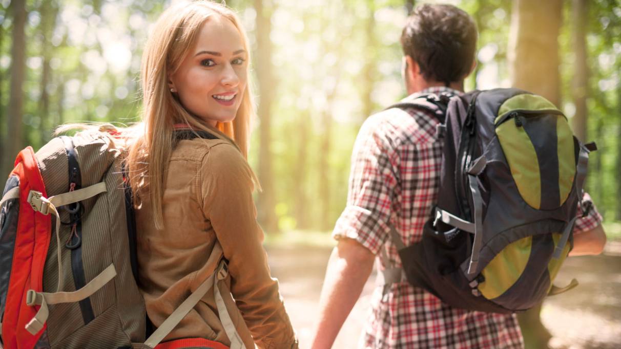 a couple hiking with backpacks in the woods