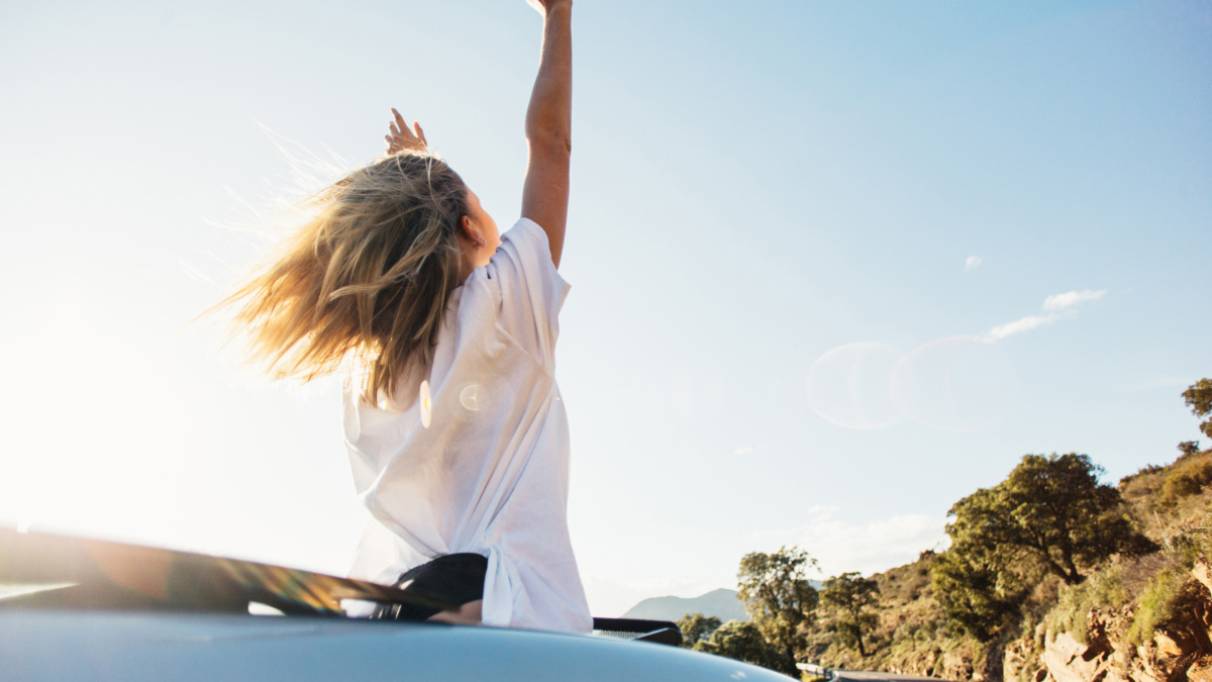 lady waving her arms in an open top car