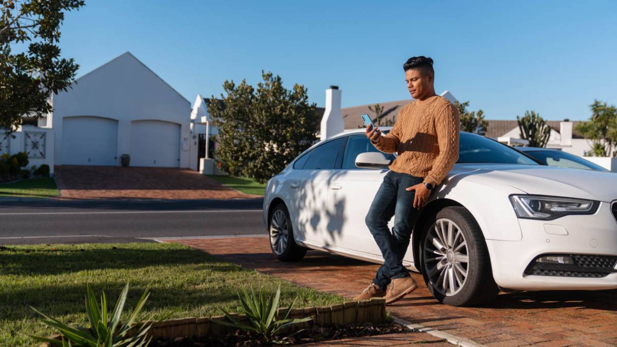 a person leaning on a parked car looking at a phone