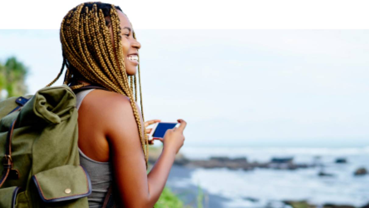 Woman enjoying the view whilst preparing to take a camera phone image of the coastline