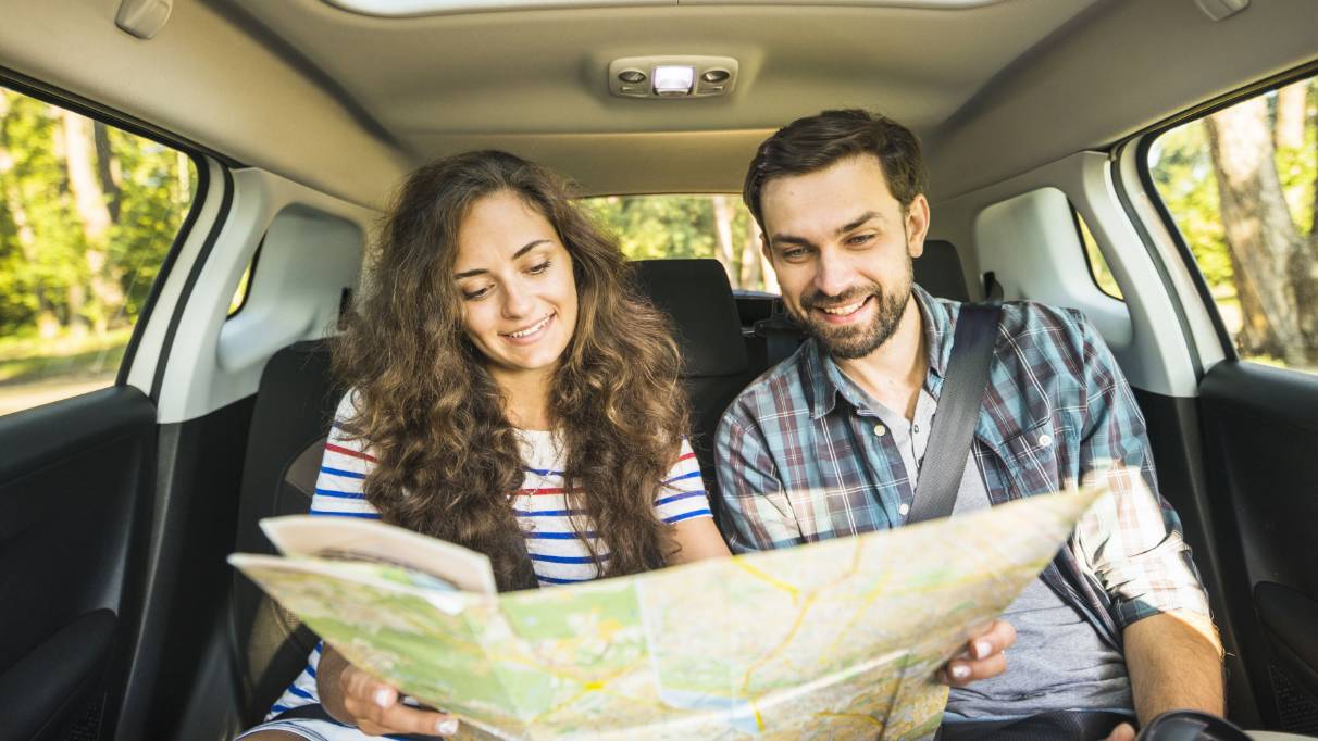 Two people sitting in the back of a parked car looking at a map