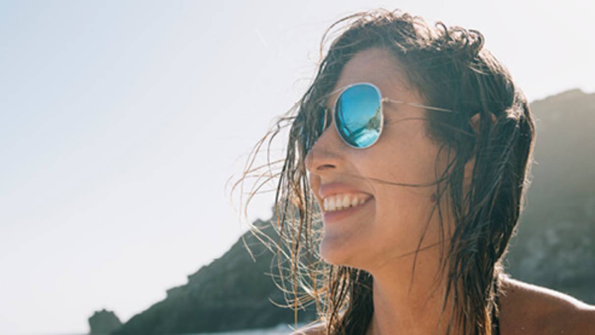 Woman wearing sunglasses and smiling with mountains in distance