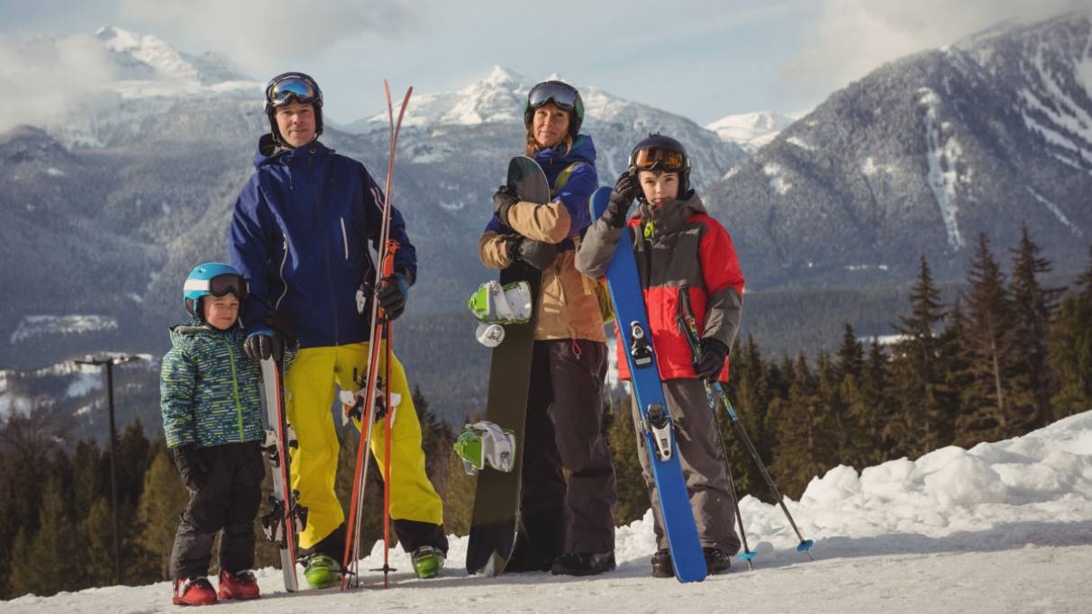 a family of four in a mountain landscape with winter sports gear