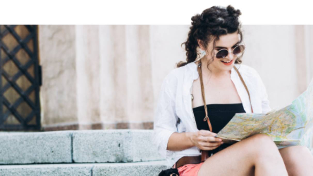 Woman in a city centre location sitting on some steps reading a map