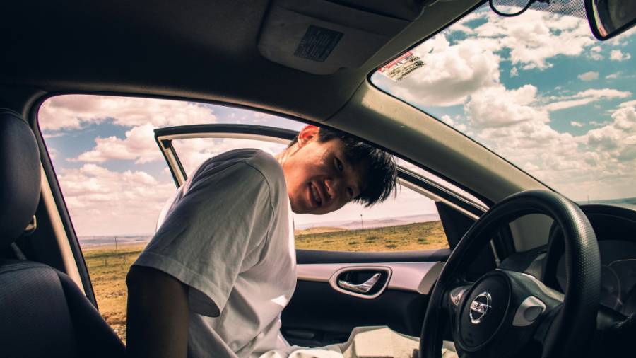 a person in a white t shirt getting into a car in a desert landscape
