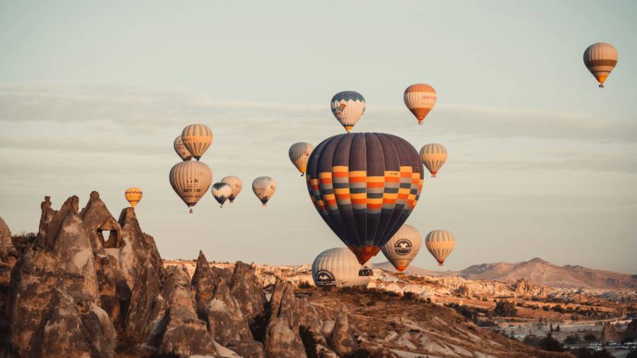 Colourful hot air balloons rise above a mountain range