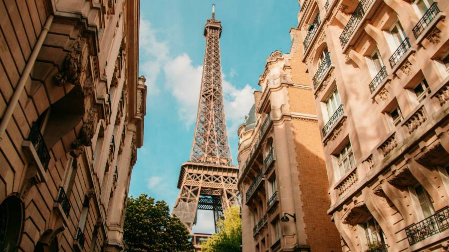 Looking up at Eiffel Tower in Paris from between two rows of buildings during daytime