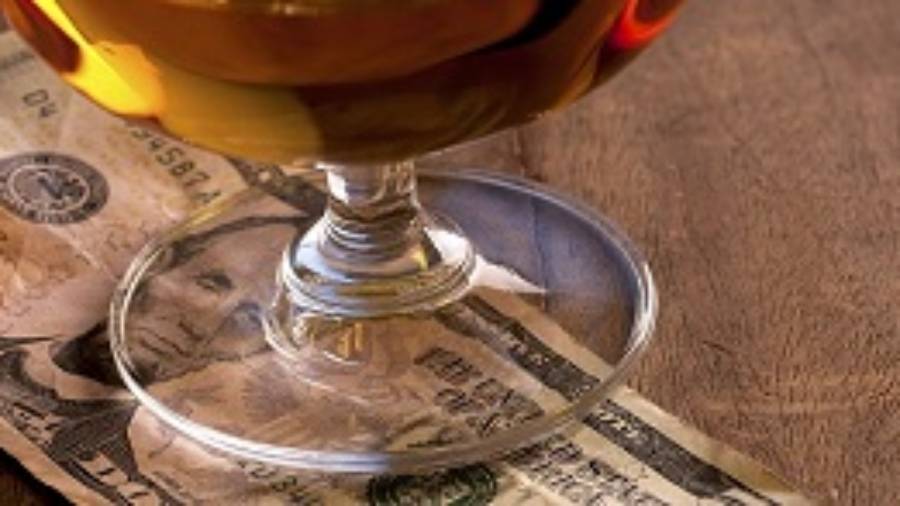 a glass of cognac placed atop a five dollar bill