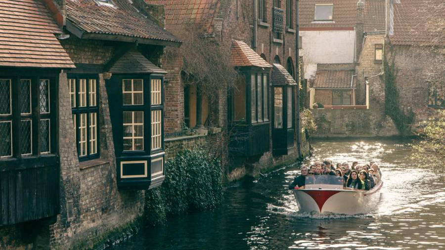 A group of people in a boat on a narrow canal behind old buildings