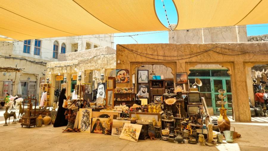 Market stall with antiques and art in Dubai’s Al Fahidi Historical District, set under shade sails with traditional buildings in the background