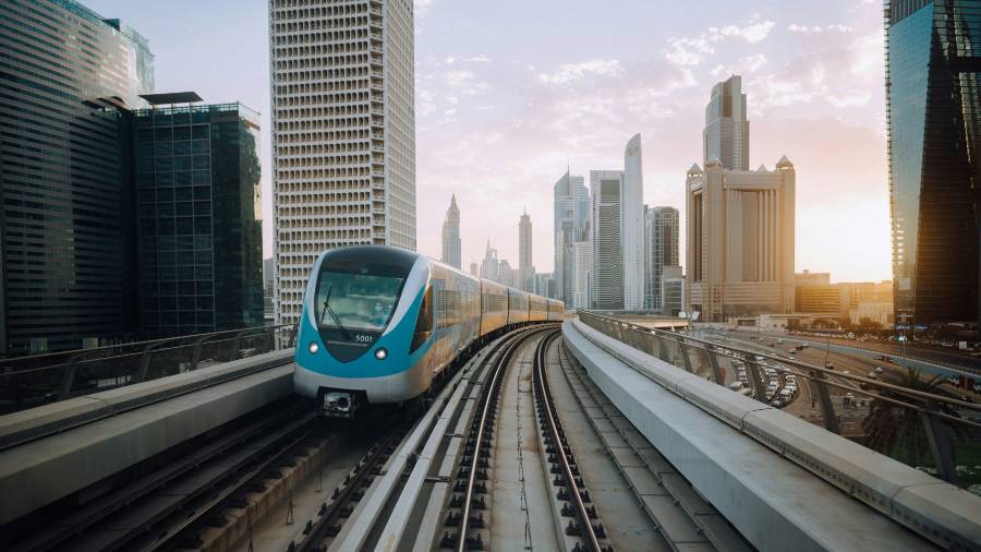 Dubai Metro train on elevated tracks with city skyline at sunset