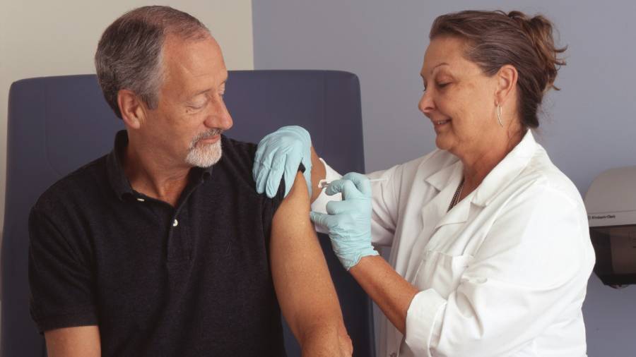 Man in black polo shirt being treated by doctor