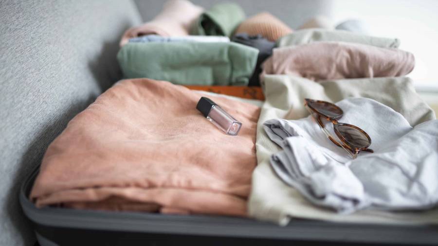 An open suitcase showing clothing, cosmetics and sunglasses
