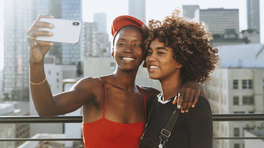 A couple of women taking a selfie against a city backdrop