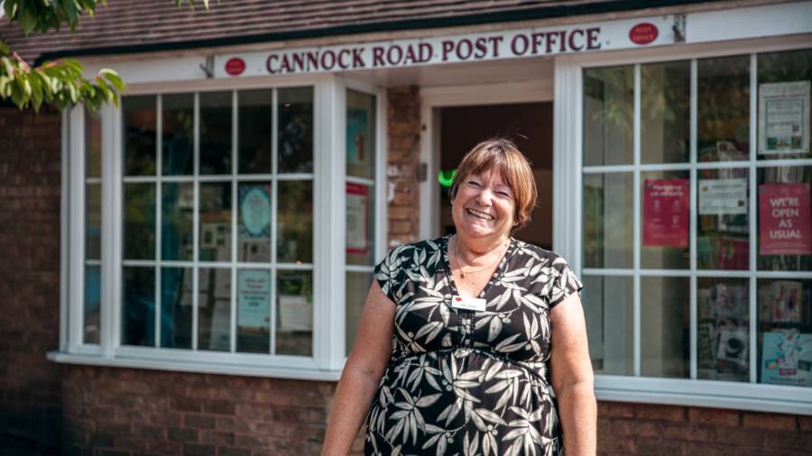 A smiling member of the Post Office team outside her Post Office branch in Cannock Road