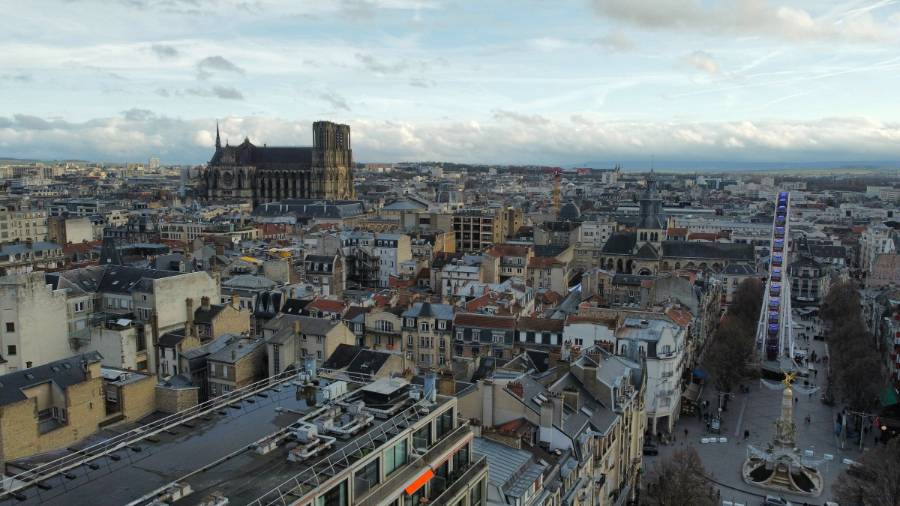  Aerial view of a city from the top of a building, with a cathedral and a Ferris wheel in the distance