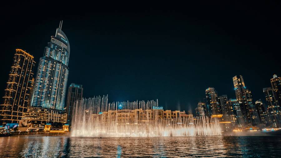 Dubai Fountain at night with lit water jets and tall buildings in the background