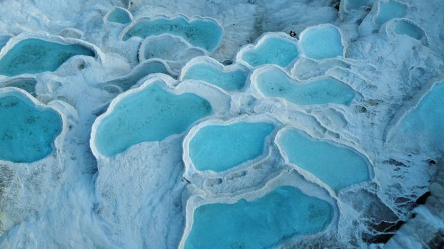 Looking down on a group of white rocks with pools of pale blue water