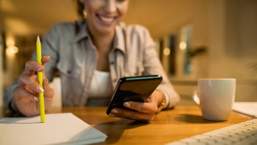 Closeup of woman using smart phone while learning in the evening at home