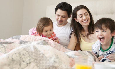 Young family laughing in bed together