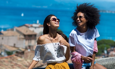 Two women laughing, enjoying each other's company, behind them, the sea view from above