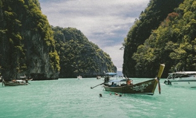 Lagoon with boats surrounded by rocky green hillside in Thailand