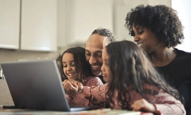 a family of four happily sitting in front of a laptop