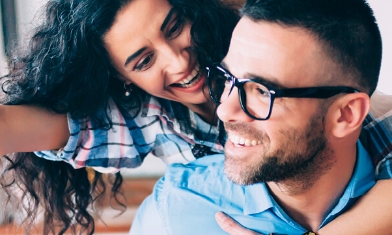 Young couple in kitchen both smiling while woman holds dangling key out in front of man