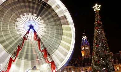 The big wheel on the the left and a Christmas tree on the right at night